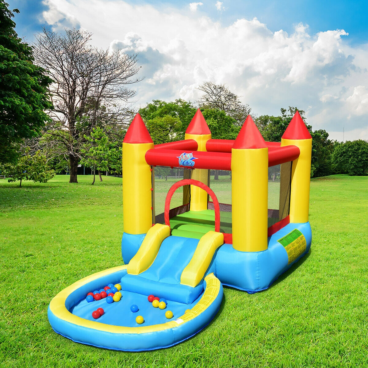 Colorful inflatable bounce house with slide and ball pit on green grass under blue sky