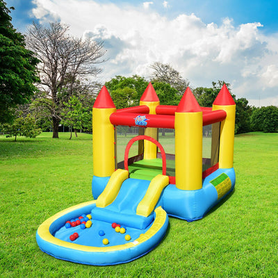Colorful inflatable bounce house with slide and ball pit on green grass under blue sky